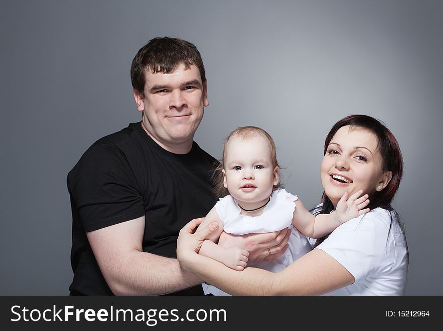 Closeup family portrait of a young loving couple holding cute baby. Closeup family portrait of a young loving couple holding cute baby