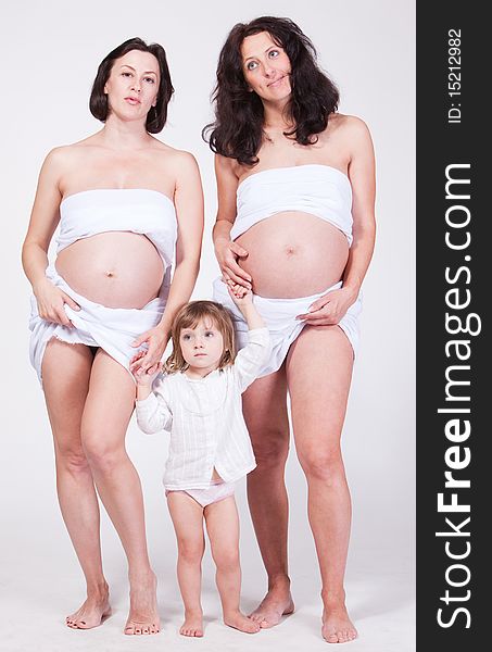 Studio portrait of two happy pregnant women keep the cute child arm