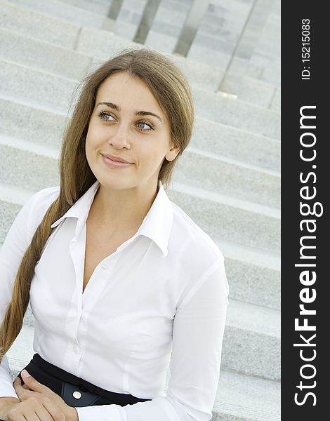 Contemporary portrait of a young professional business woman smiling on the background of the stairs and office space. Contemporary portrait of a young professional business woman smiling on the background of the stairs and office space