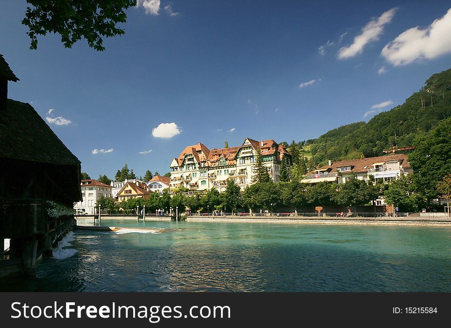 A building by the Aare River in the Swiss town of Thun. To the left the river is slowed down by a barrage.