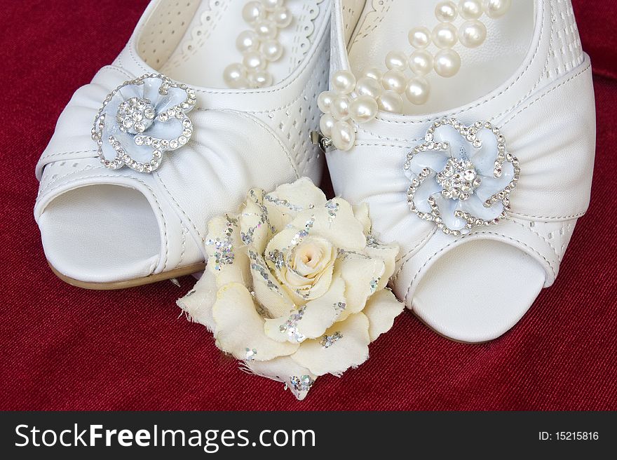 Beautiful wedding shoes with pearls and flower on red background