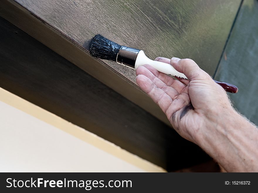 A man gently paints a part of his house, while in the background a piece of the unpainted wood is still visible. A man gently paints a part of his house, while in the background a piece of the unpainted wood is still visible.