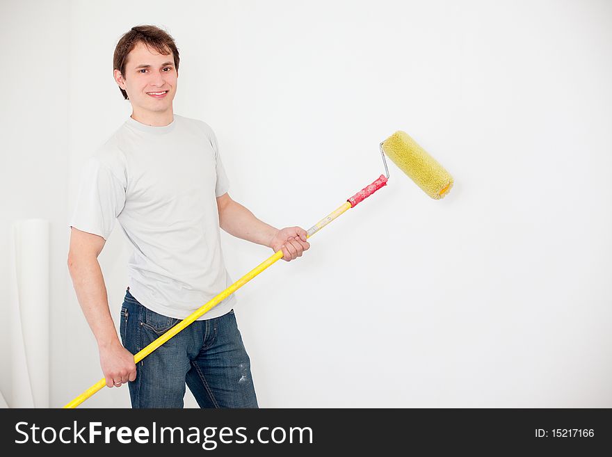 Young smiling man painting a wall. Young smiling man painting a wall