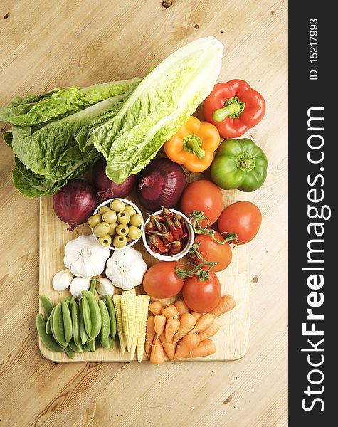 Vegetables on a wooden kitchen table, lit with a large light source from the right.