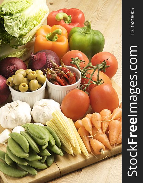 Vegetables on a wooden kitchen table, lit with a large light source from the right.