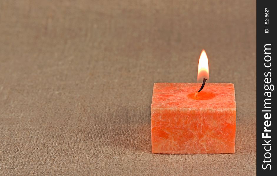 Orange aromatic candle on the fabric background