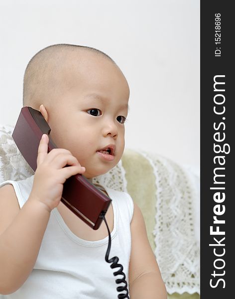 A Chinese baby with a telephone in home. A Chinese baby with a telephone in home.