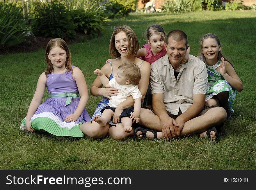 Young family on the grass at the backyard. Young family on the grass at the backyard.