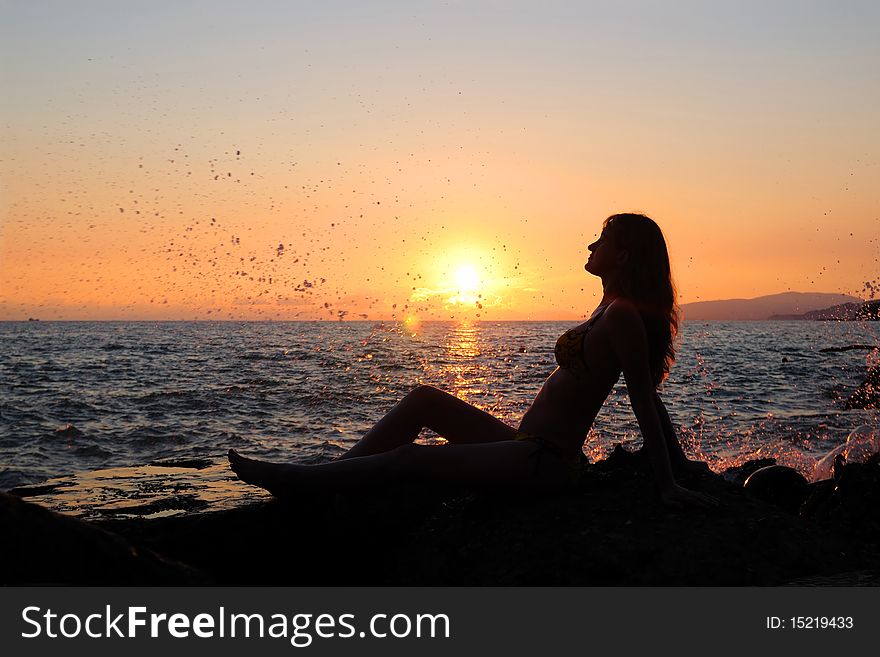 The girl sits on stones. Enjoys a decline. The girl sits on stones. Enjoys a decline