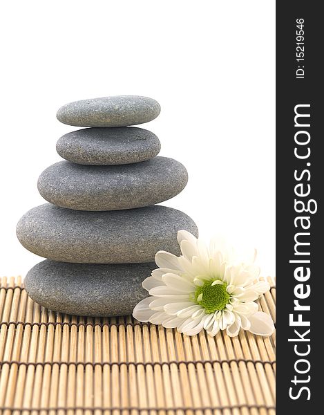 White flower with stack of pebbles on mat. White flower with stack of pebbles on mat
