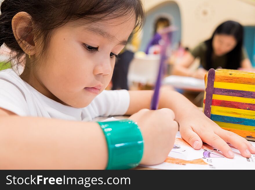 Kids are painting picture with color pencil with their teacher in the classroom to learn paint skill. they are practicing the imagine lesson workshop