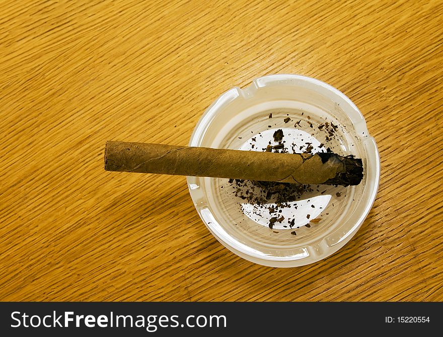 Cigar which only have set fire, lying in a white ashtray. Cigar which only have set fire, lying in a white ashtray