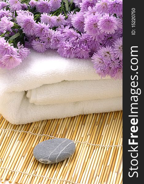 Towel with pink daisy and stone on mat. Towel with pink daisy and stone on mat