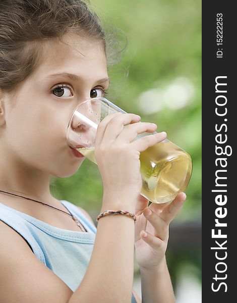 Portrait of nice little girl drinking juice in summer environment