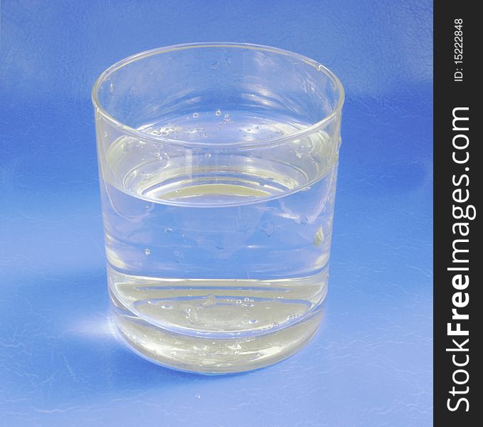 Cold, carbonated mineral water in a clear glass beaker on blue background. Cold, carbonated mineral water in a clear glass beaker on blue background