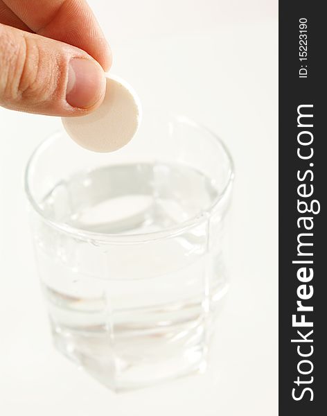 Tablet of sedative in a hand above a glass with water
