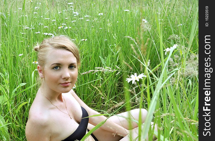 The beautiful girl with blue eyes in a grass