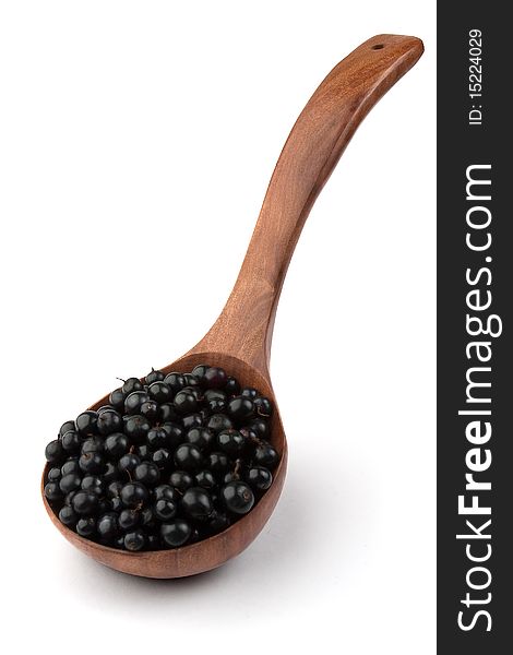 Black currant in a wooden spoonl isolated with a path