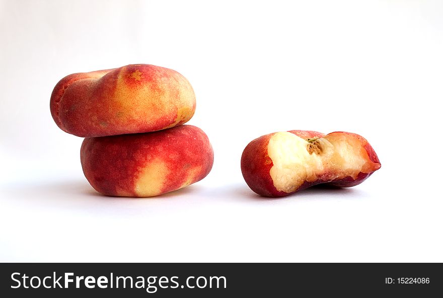 Three flat peaches: whole and taken a bite (close-up)