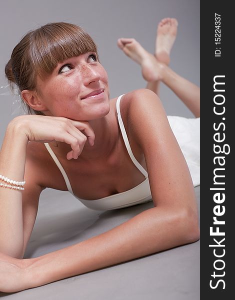 Happy woman in white dress posing on the grey background