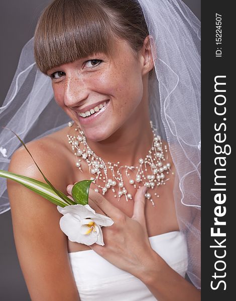 Laughing bride with flower over grey background