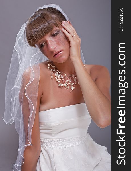 Portrait of crying bride over grey background