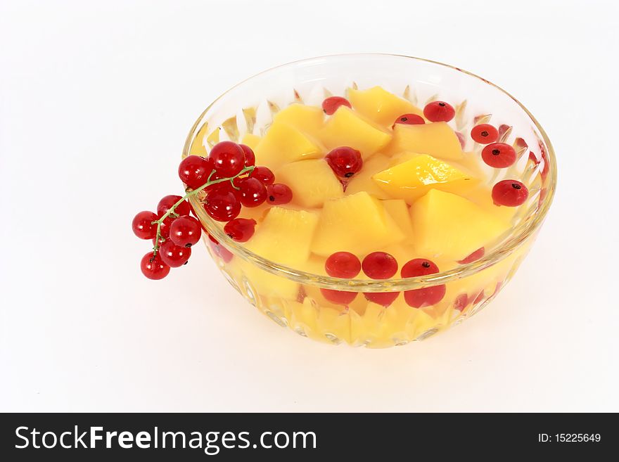 Peach compote with fresh red currants in glass bowl isolated on white