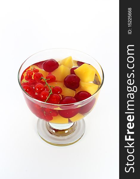 Peach compote with fresh red currants and sour cherries in glass bowl isolated on white