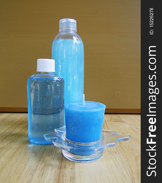 Two soap blue bottles with blue votive candle on a wooden table. Two soap blue bottles with blue votive candle on a wooden table.