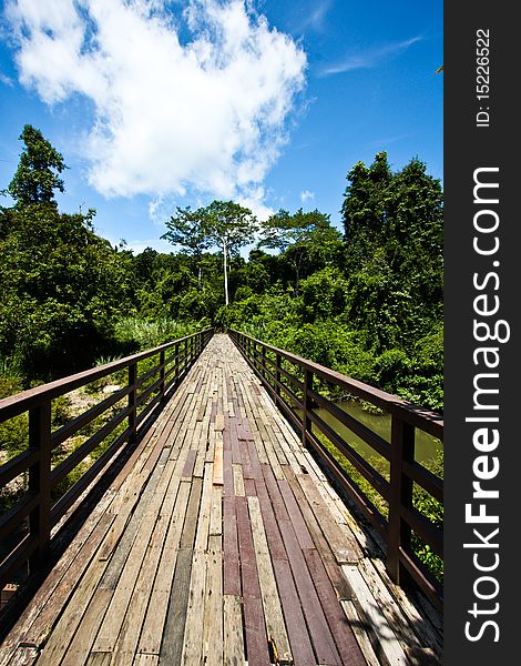 Wooden bridge lead to jungle in Thailand under blue sky. Wooden bridge lead to jungle in Thailand under blue sky