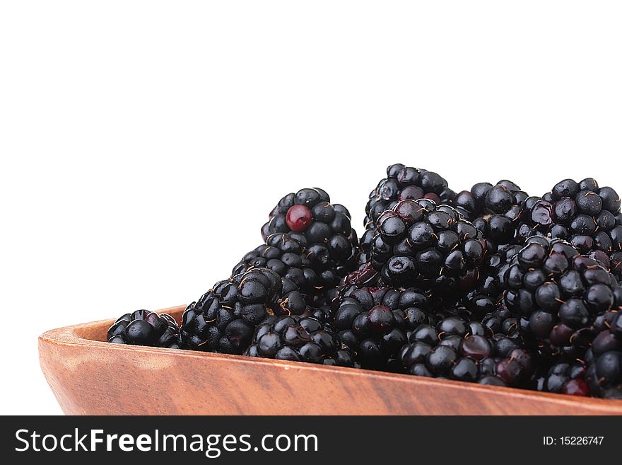 Blackberry - berries of black colour in a wooden plate on a white background. Blackberry - berries of black colour in a wooden plate on a white background.
