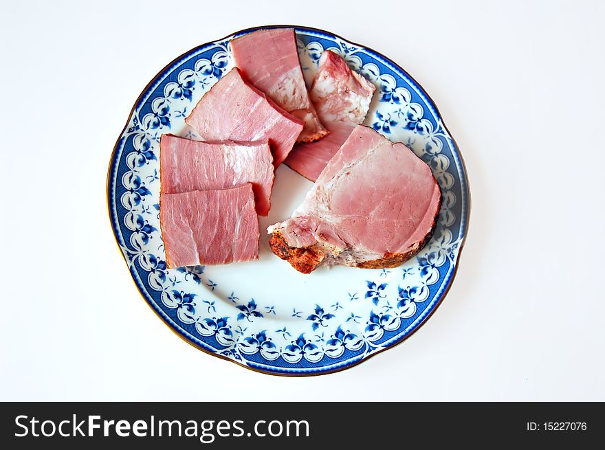 Ham sliced on a plate with a light shade on white background. Ham sliced on a plate with a light shade on white background
