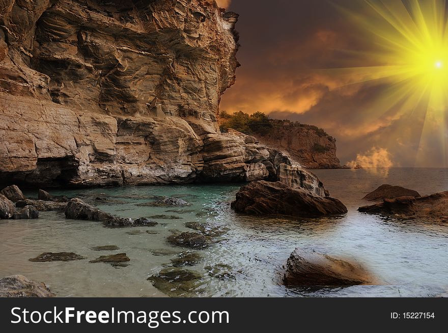 Island in Greece on a cloudy day with sun rays piercing the sky. Relaxing scenery with cliffs. Island in Greece on a cloudy day with sun rays piercing the sky. Relaxing scenery with cliffs