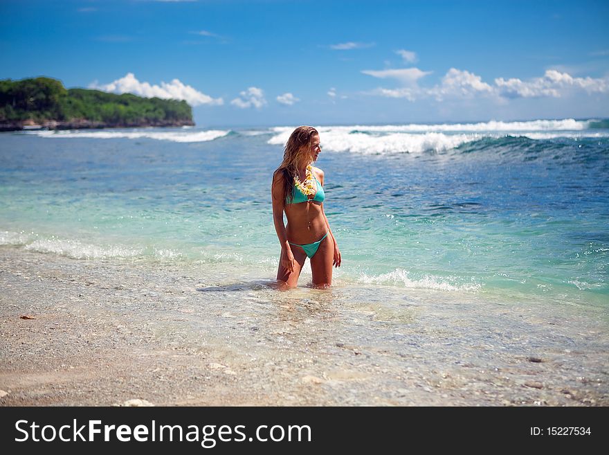 Young model blond girl standing in water on the beach