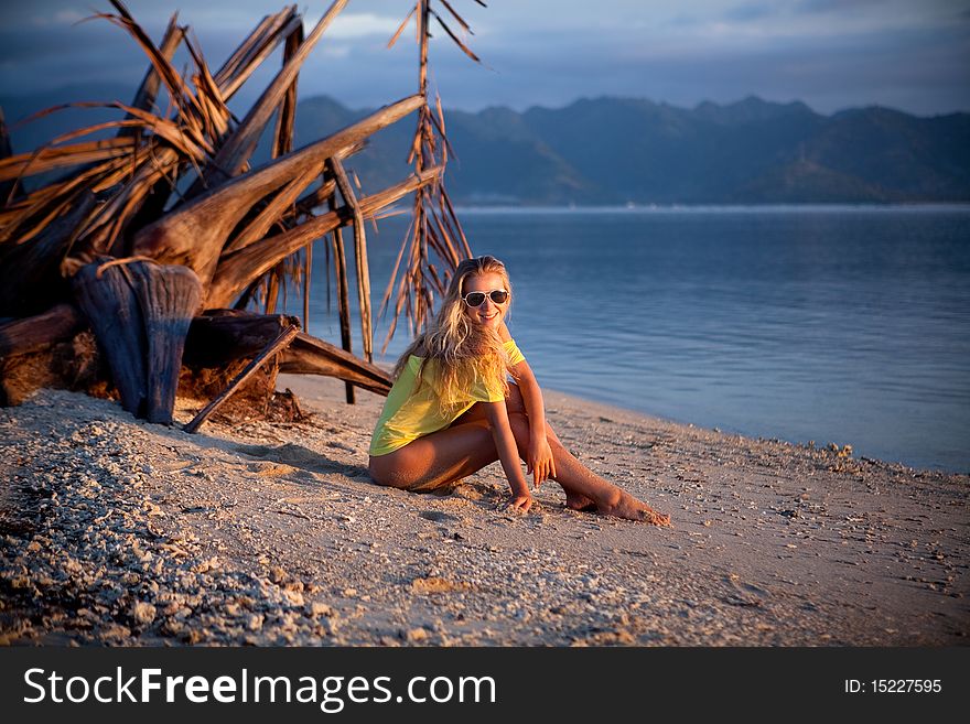 Young model blond girl sitting on the beach. Young model blond girl sitting on the beach
