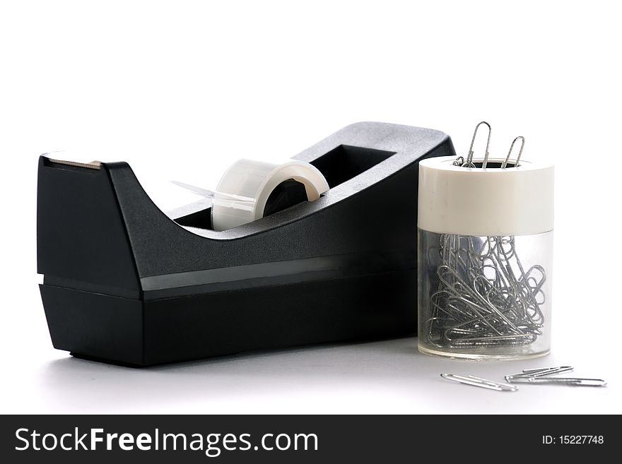 A cellophane tape dispenser with a magnetic paper clip dispenser. Isolated on white. A cellophane tape dispenser with a magnetic paper clip dispenser. Isolated on white.