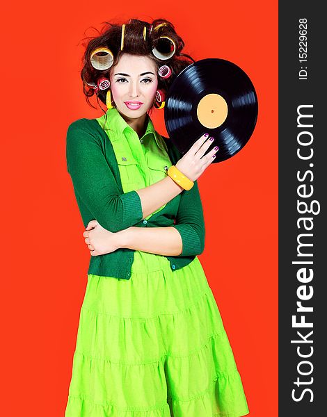 Portrait of a woman with curlers on her hair holding gramophone record. Retro style.