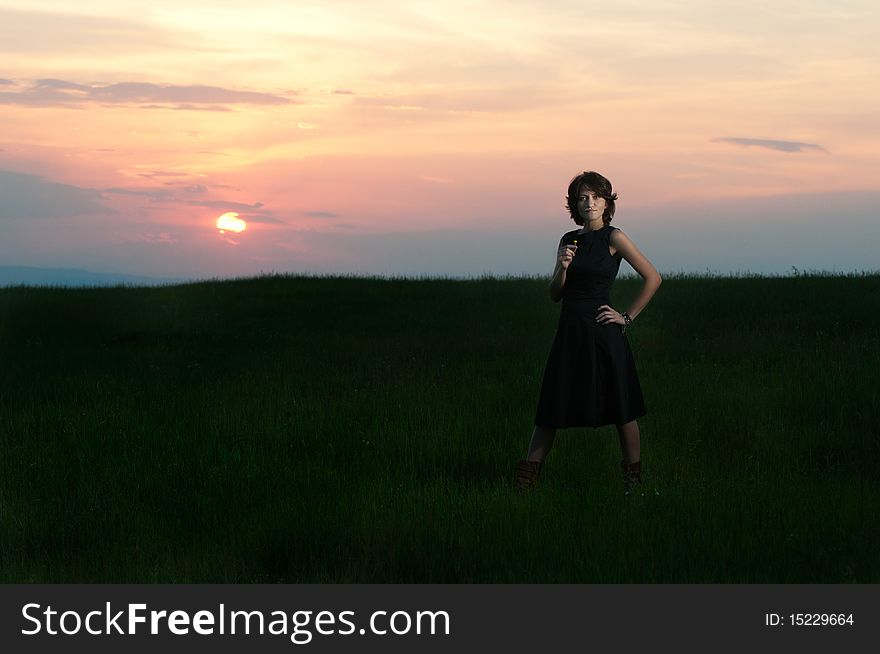 Photo of a young beautiful woman in a green wheat field at sunset. Photo of a young beautiful woman in a green wheat field at sunset
