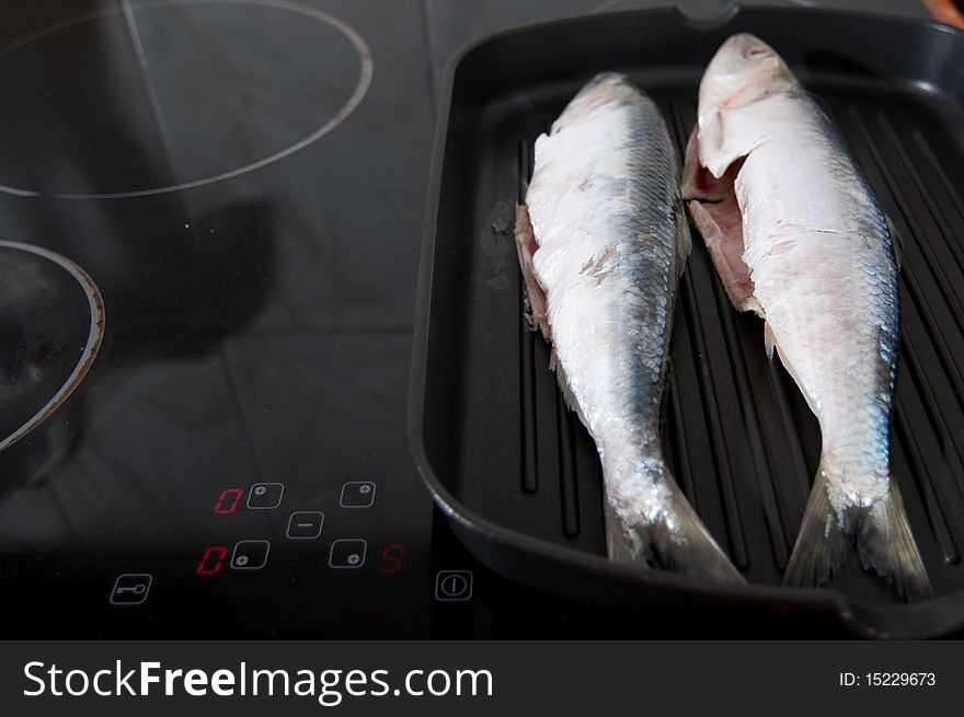 Two fishes cooked in a fry pan at maximum temperature. Two fishes cooked in a fry pan at maximum temperature