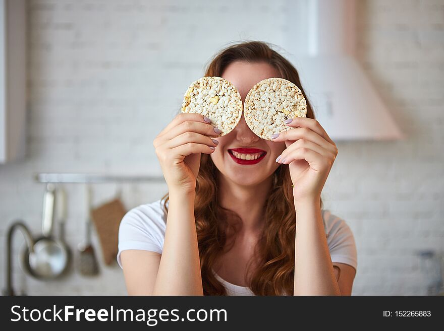 Young woman eating rye cracker crisp bread in the kitchen. Healthy Lifestyle. Health, Beauty, Diet Concept