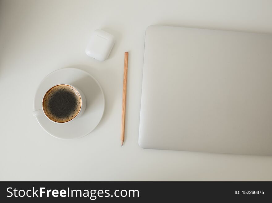 White office table on which laptop, coffee, tablet, camera and other items