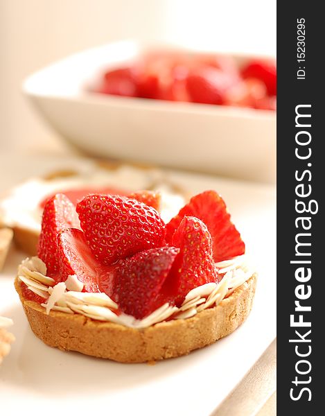 Small tartelettes with strawberries and almonds on a white plate