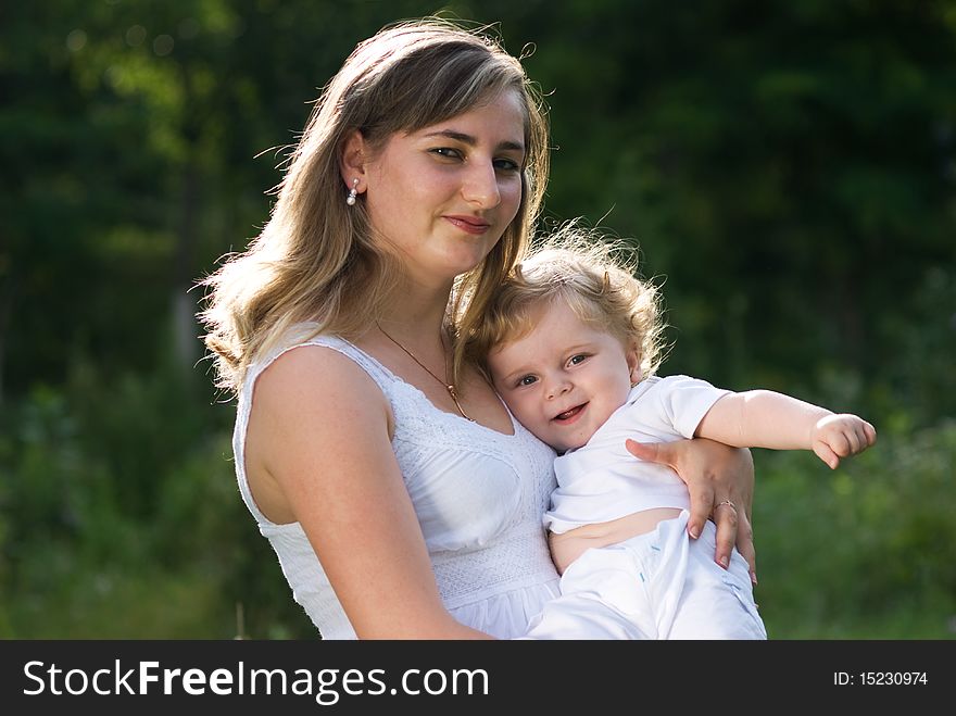 A young attractive woman holds her little cute baby in his hands. A young attractive woman holds her little cute baby in his hands