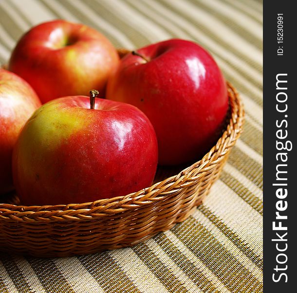 Ripe red apples in the basket on the tablecloth