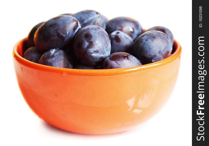 Juicy plums on the plate isolated on white background with drops of water