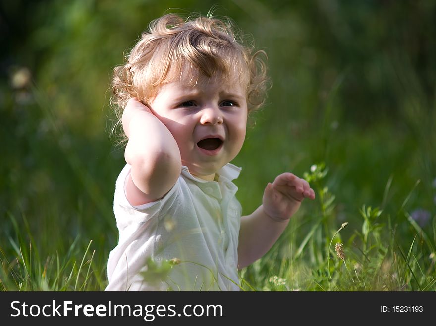 Little cute baby crying alone in the green grass. Little cute baby crying alone in the green grass