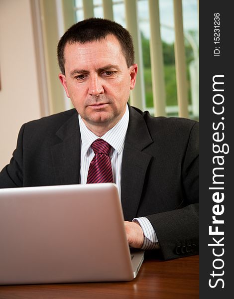 Successful businessman working on a laptop in the office. Successful businessman working on a laptop in the office