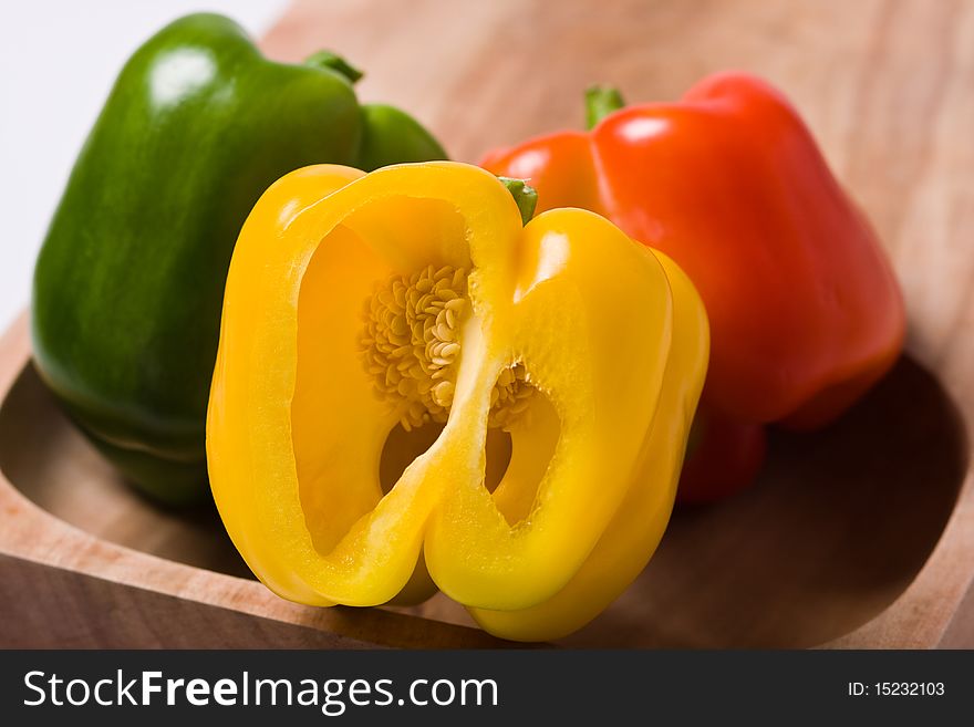 A red and green bell pepper flanking a yellow pepper with a slice missing and the seeds showing. A red and green bell pepper flanking a yellow pepper with a slice missing and the seeds showing
