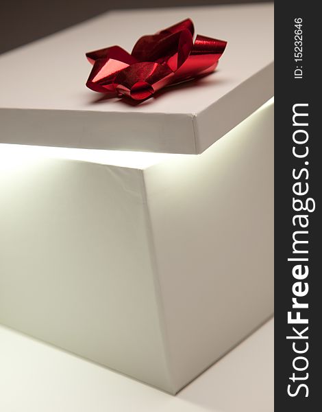Gift Box with Red Bow Lid Revealing Very Bright Contents on a Gradated Background. Gift Box with Red Bow Lid Revealing Very Bright Contents on a Gradated Background.