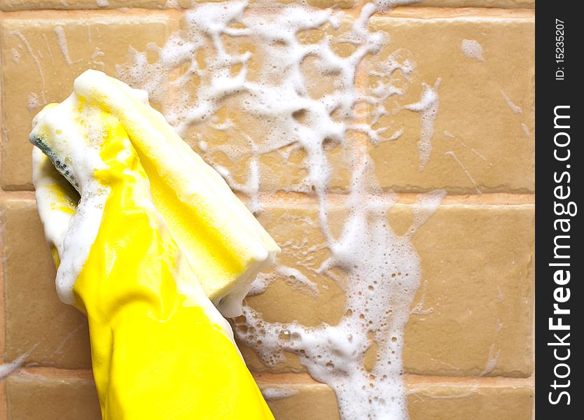 Hand in yellow rubber glove holding soapy cleaning sponge